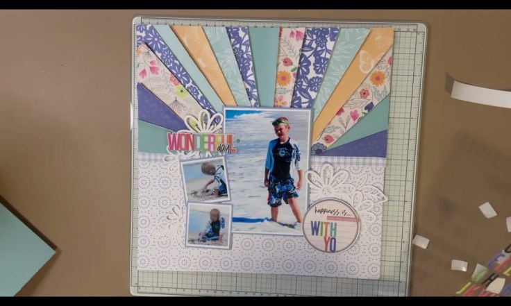 Step 8: Add Shimmer and Final Embellishments - the finished sunburst scrapbook layout with shimmered die-cut flowers, photos, and colorful puffy alpha title