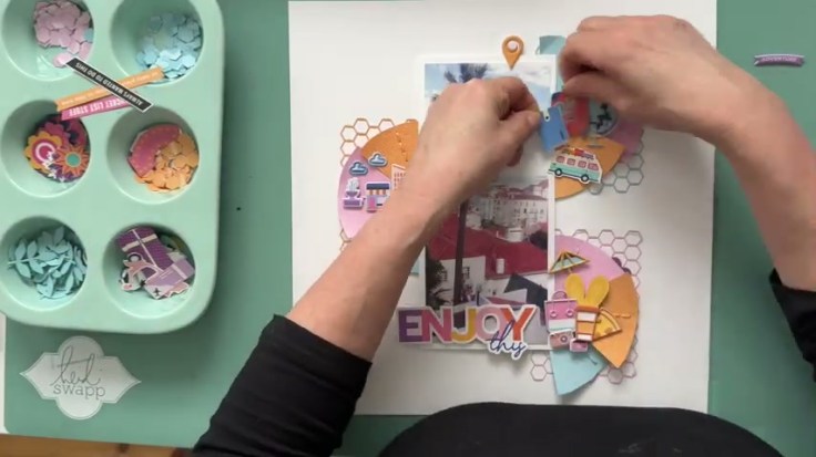 Step 7: Add Fussy-Cut Travel Icons - placing the bus rub-on and suitcase die cut travel icons on the scrapbook layout
